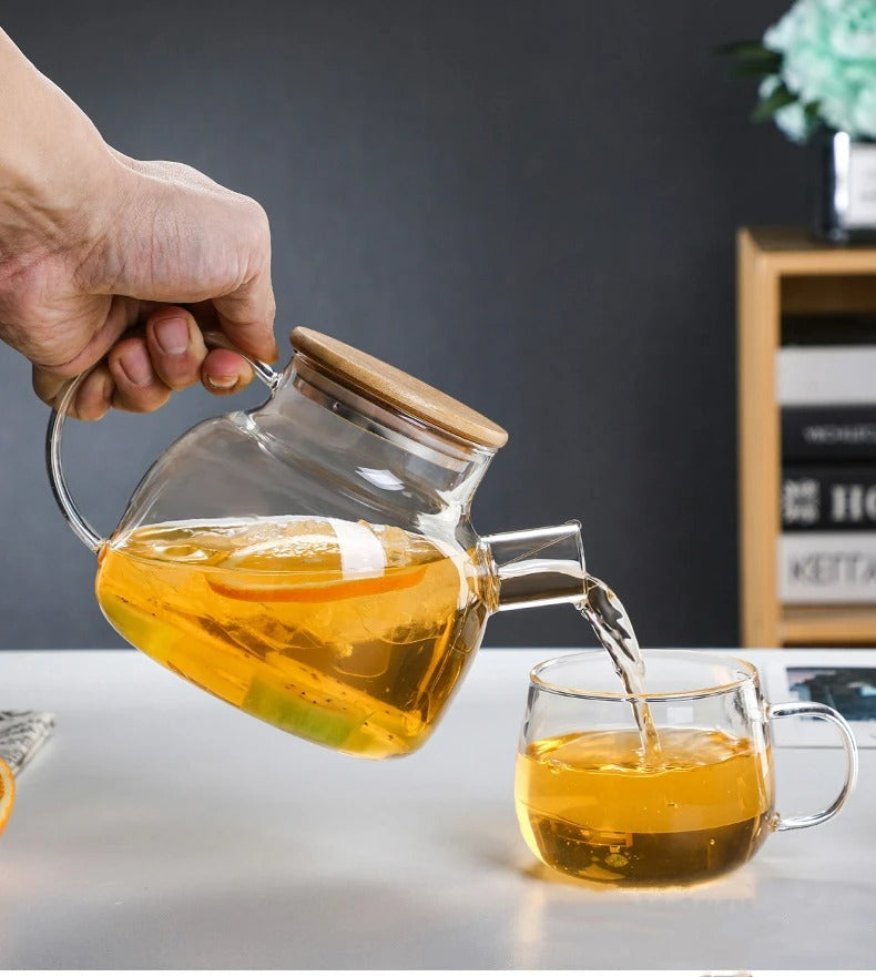 Théière en verre avec couvercle en bambou servant une infusion aux agrumes et kiwi dans une tasse transparente 2